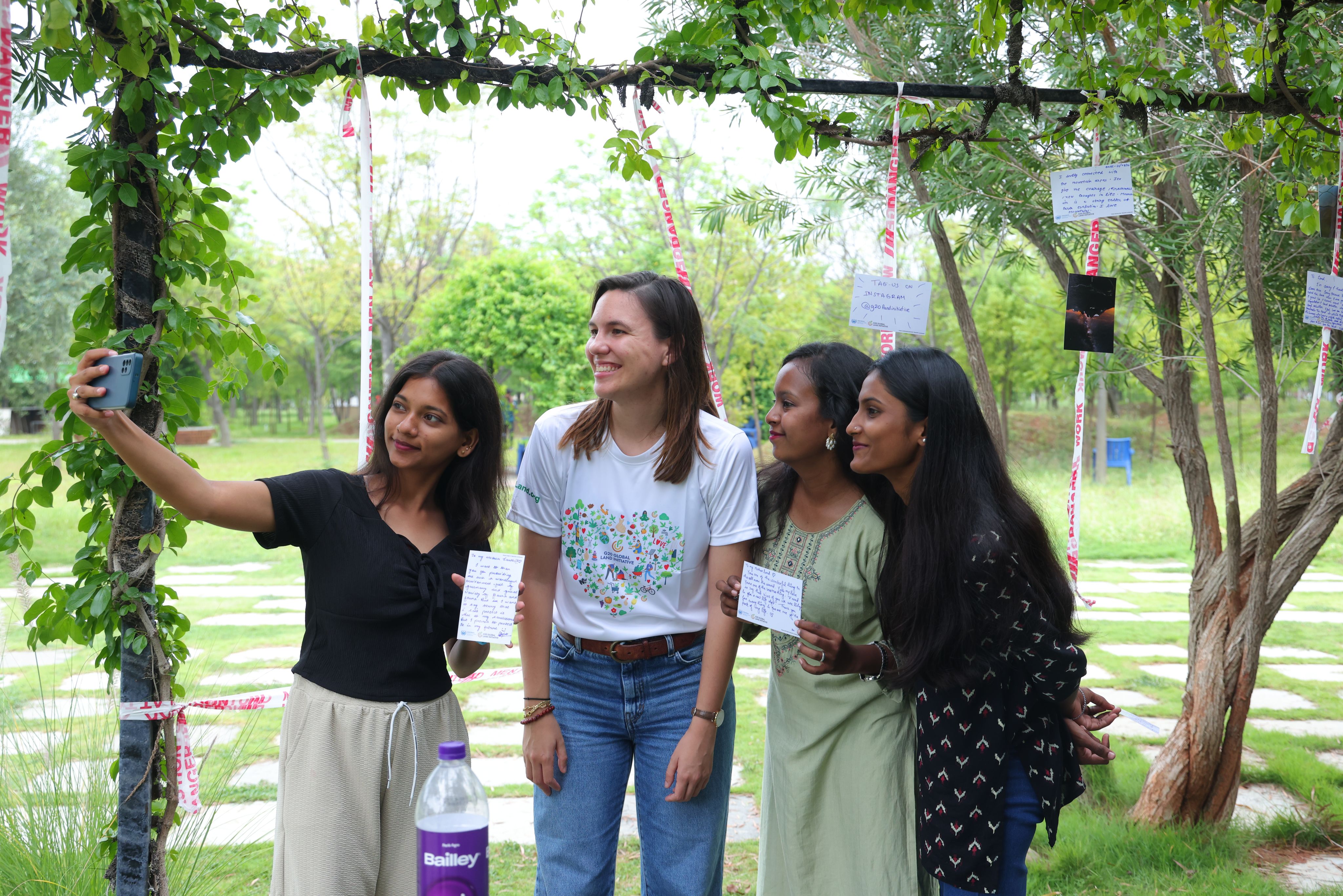 A young woman takes a selfie with other three